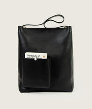 Load image into Gallery viewer, Watoji I Nasch Bag L I black I frontal view, open outside pocket with the book "The Beauty of Everyday Things I white background