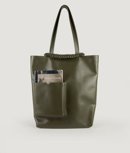Pazar Book Tote bag from Italian calf leather in olive green. Hand braided signature leather handle functioning as a fastening detail. The outside pocket is designed for a book. This size is suitable for A4 format, all MacBook and iPad sizes.