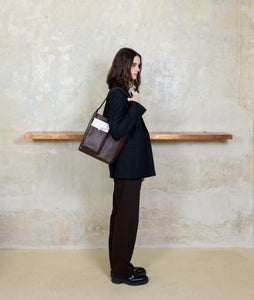 Watoji I Nasch Bag S I dark brown I from asideI Woman carries the bag over her shoulder at SAGAN Shop Vienna.