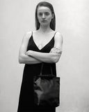 Load image into Gallery viewer, Pazar I Pazar Tote Nano Black I black I front view I showing iconic SAGAN closing system and strap detail I wearing by a model I black and white picture
