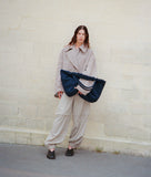 Load image into Gallery viewer, Pazar Tote XL Navy plant dyed nylon mood picture I French Lady is wearing the bag casually with one hand under her arms leaning against a wall in Paris.