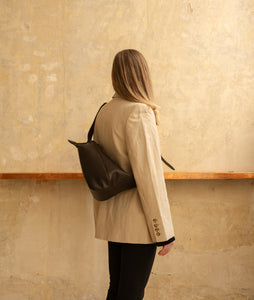 Furoshiki Crossbody Bag M Smooth Cow Leather Black I front view I white background I model wearing bag over her shoulder at SAGAN Vienna Shop